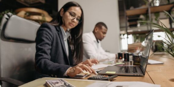 Een ondernemer die een zakelijke rekening vergelijkt voor zijn webshop, met laptop en notities op tafel.
